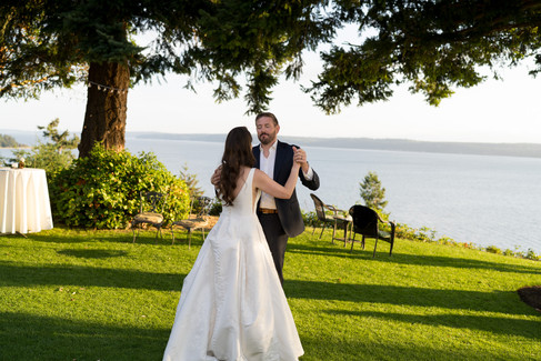 Bride and groom dancing outdoors, beautiful waterfront wedding celebration.