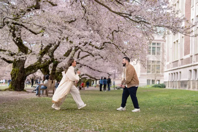 Couple playfully interacting under cherry blossoms