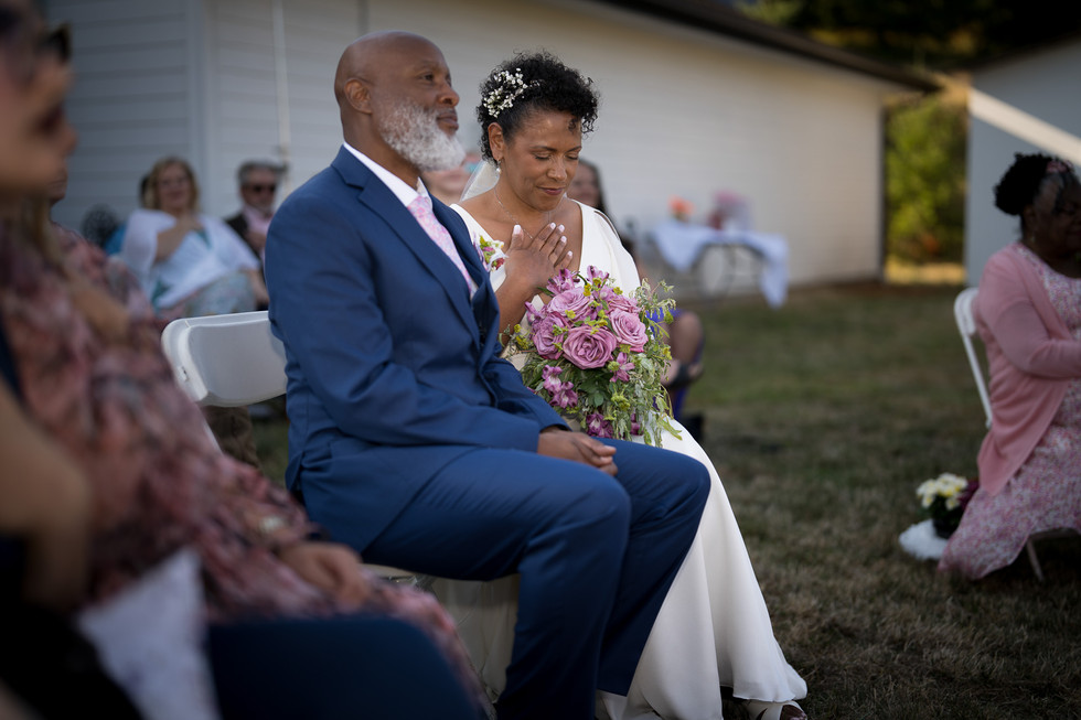 Emotional bride and groom seated at their intimate farm wedding.
