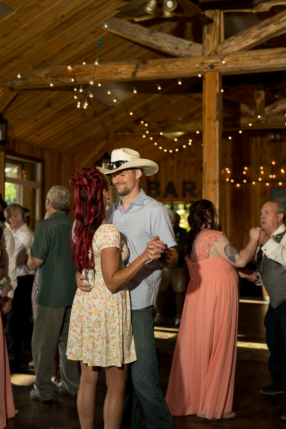 Couple dancing at BAR rustic wedding reception with string lights.
