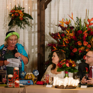 Speaker delivers toast at vibrant wedding reception with beautiful floral decor.