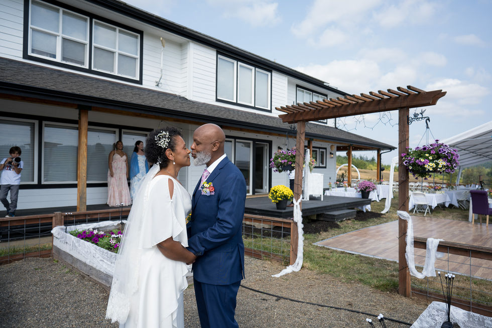 Black wedding couple holding hands at intimate farm wedding outside farmhouse.