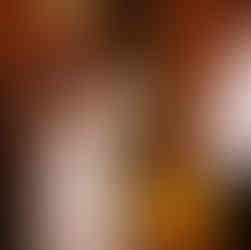 Bride in white dress embraces woman at indoor wedding reception.