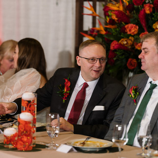 Guests in suits chatting at a lively wedding reception table.