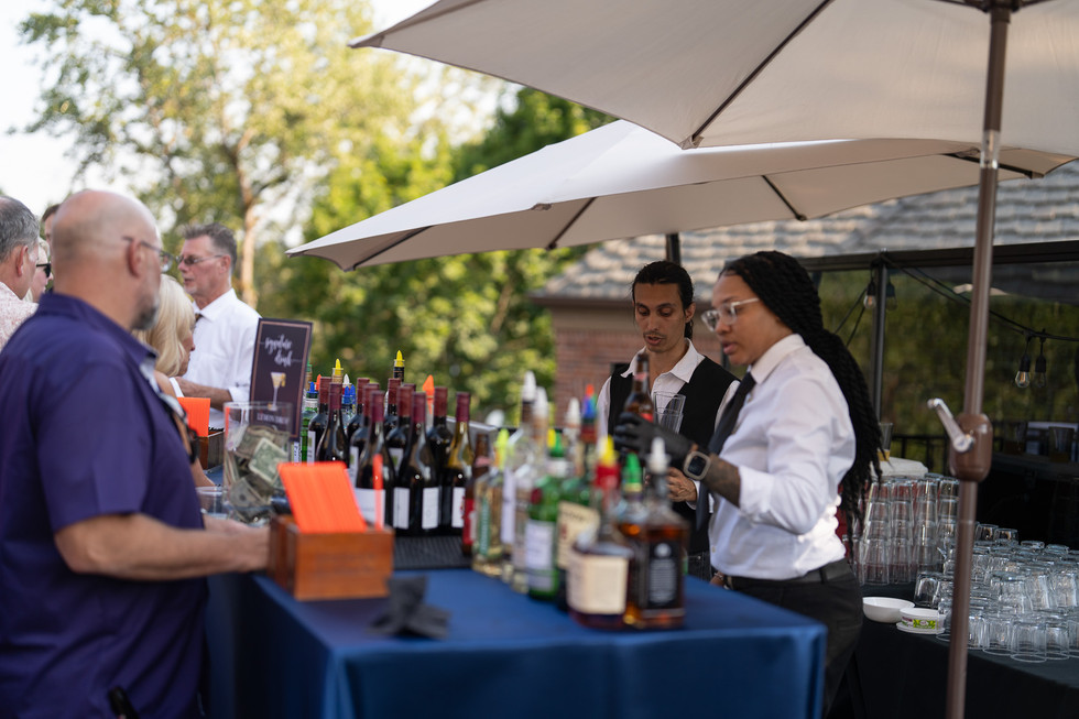 Bartenders serving "Specialty Cocktails" at an outdoor bar event.