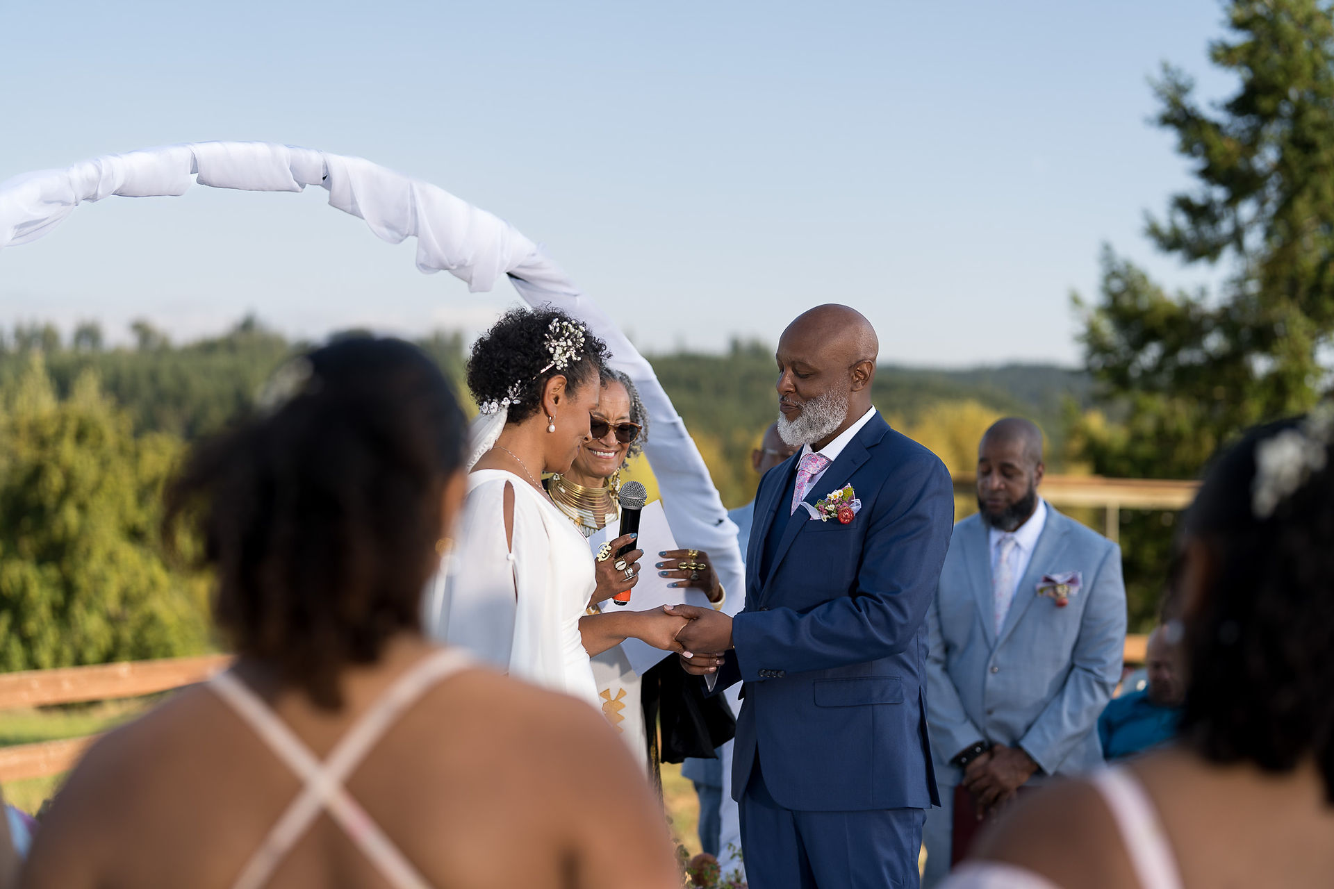 Bride and groom exchanging rings at outdoor wedding ceremony with officiant.