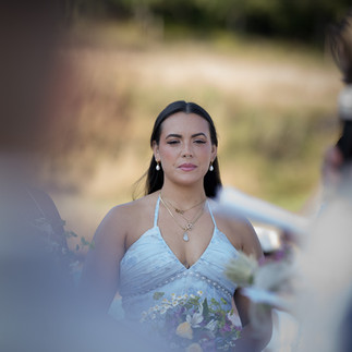 Elegant woman in white dress looks forward at intimate outdoor wedding.