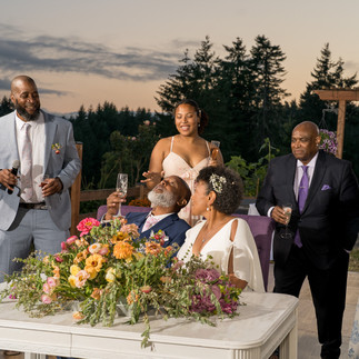 Joyful couple and guests at intimate outdoor farm wedding reception.