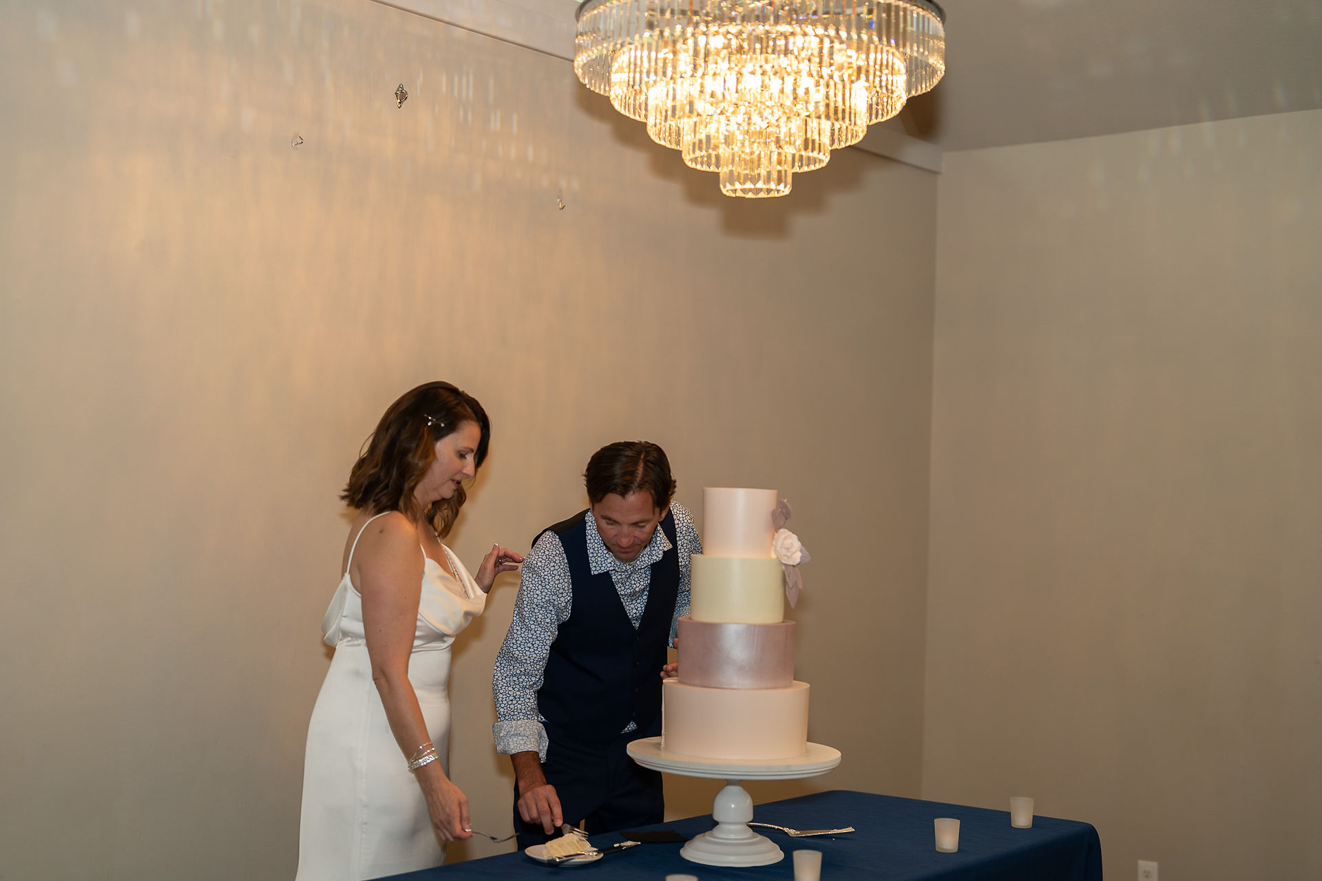 Bride and groom carefully cut their beautiful multi-tiered wedding cake.