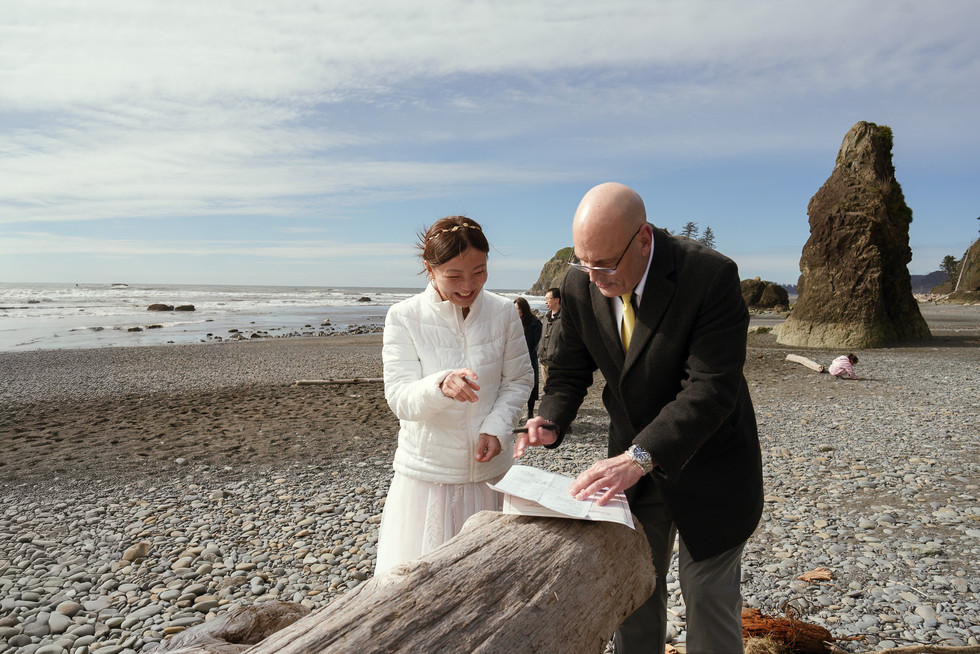 Couple signing document on Ruby Beach for Olympic National Park elopement.