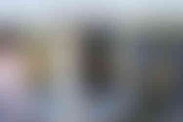 Couple exchanging rings at outdoor farm wedding, broom jumping tradition.