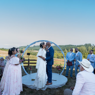 Couple shares first kiss at Intimate Farm Wedding ceremony. Guests watch.