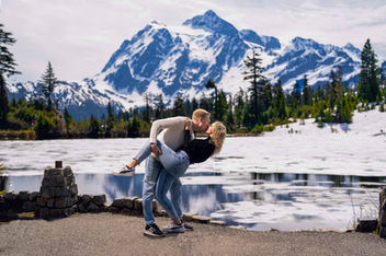 Couple kissing, man dipping woman, majestic snowy mountain, frozen lake.