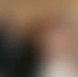 Three smiling man and women in formal attire at a wedding.