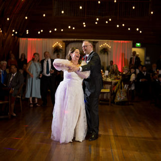 Bride and groom joyfully dancing at their wedding reception, warm lighting.