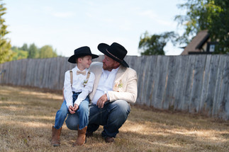 Man and young boy in cowboy hats share a tender moment.
