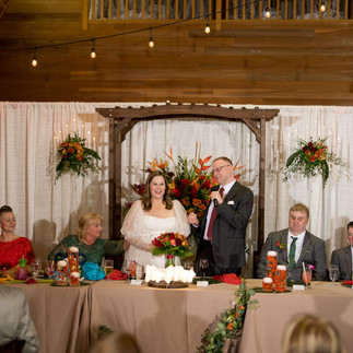 Groom speaking to bride and guests at their warm wedding reception.