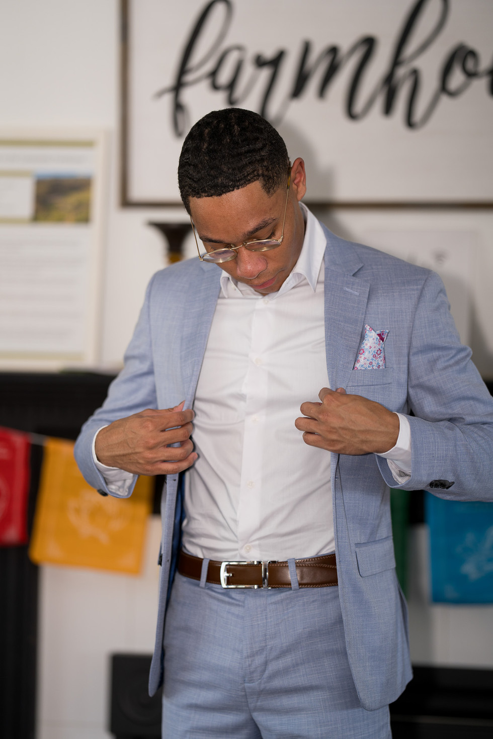 Man adjusting his crisp white shirt under a light blue suit.