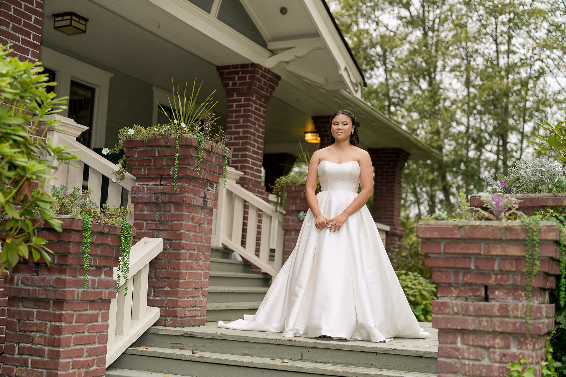 Bride in white strapless wedding dress standing on wooden steps.