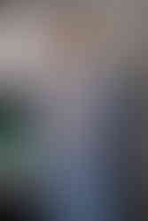 Smiling person adjusting light blue suit jacket, posing indoors.