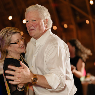 Man and woman dancing together, smiling happily at an indoor event.