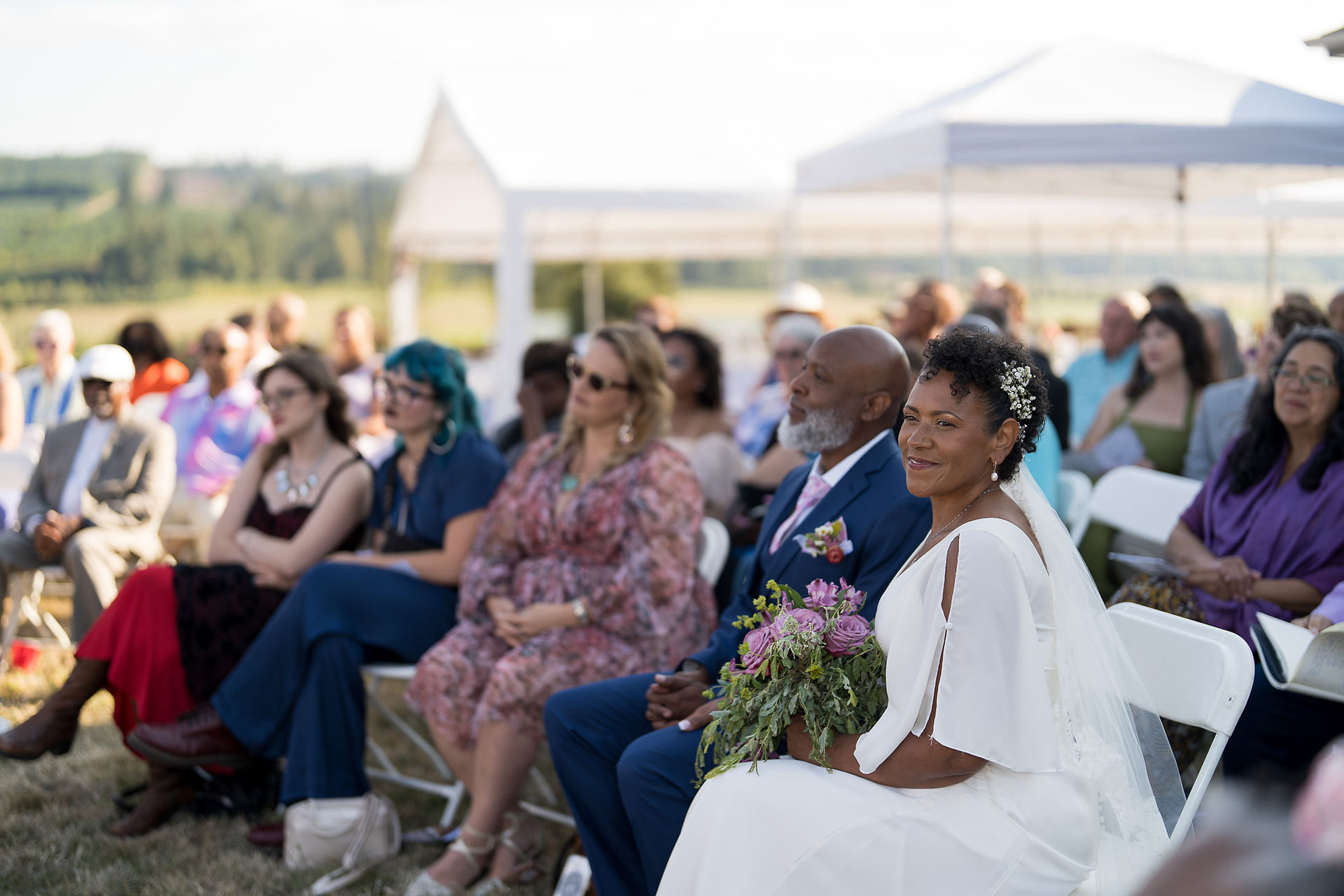 Wedding guests, bride, groom seated at an intimate farm wedding.