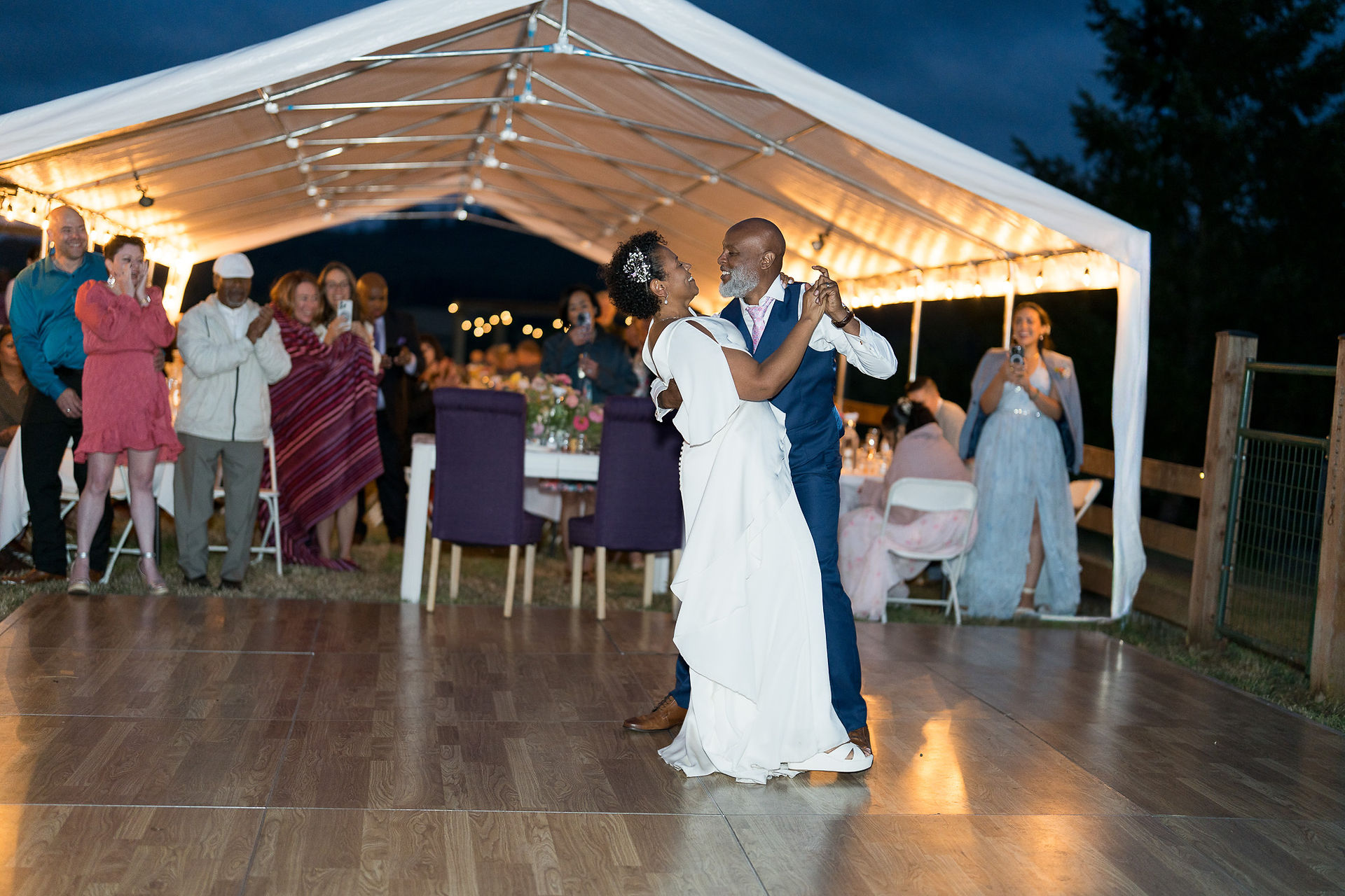 Joyful Black couple dancing at their intimate outdoor wedding reception.