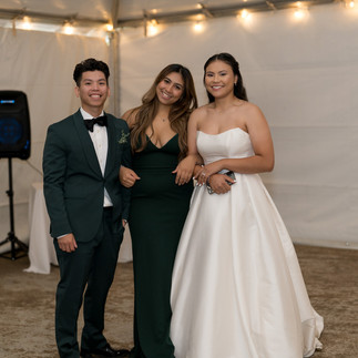 Groom, bridesmaid, bride posing happily at indoor wedding reception at Sanders Estate.