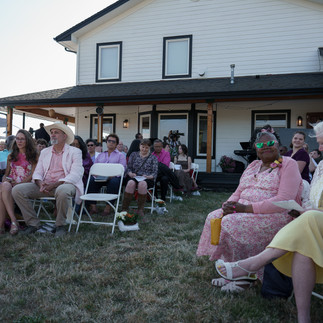Guests seated on lawn during an intimate farm wedding ceremony.