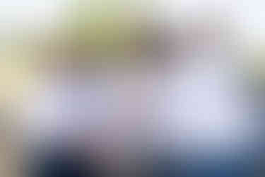 Groomsmen embracing groom in cowboy hat, laughing joyfully outdoors.