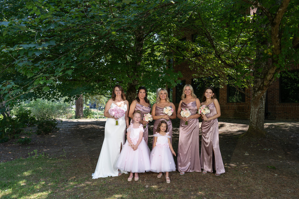 Bride, four bridesmaids, two flower girls under large tree.