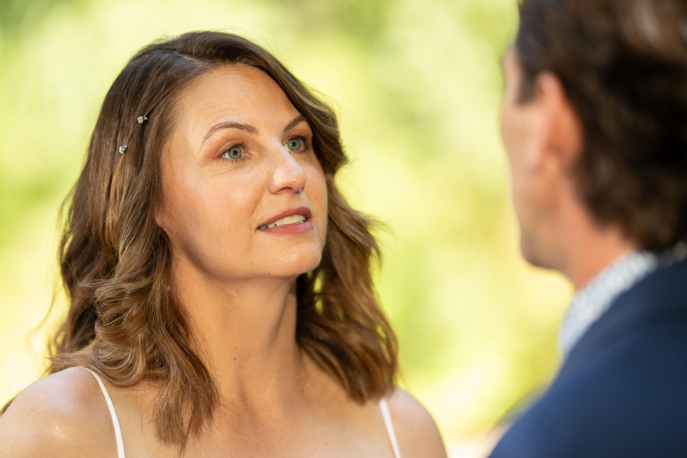 Elegant bride engaged in conversation with groom during outdoor ceremony.