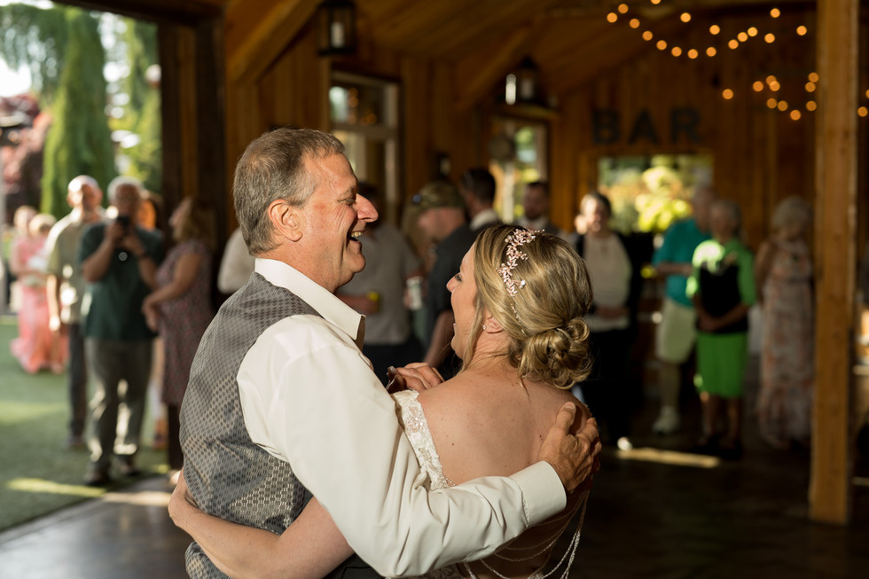 Father and bride smiling, dancing at wedding reception with BAR sign