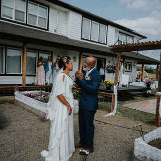Bride and older man smiling at intimate farm wedding.