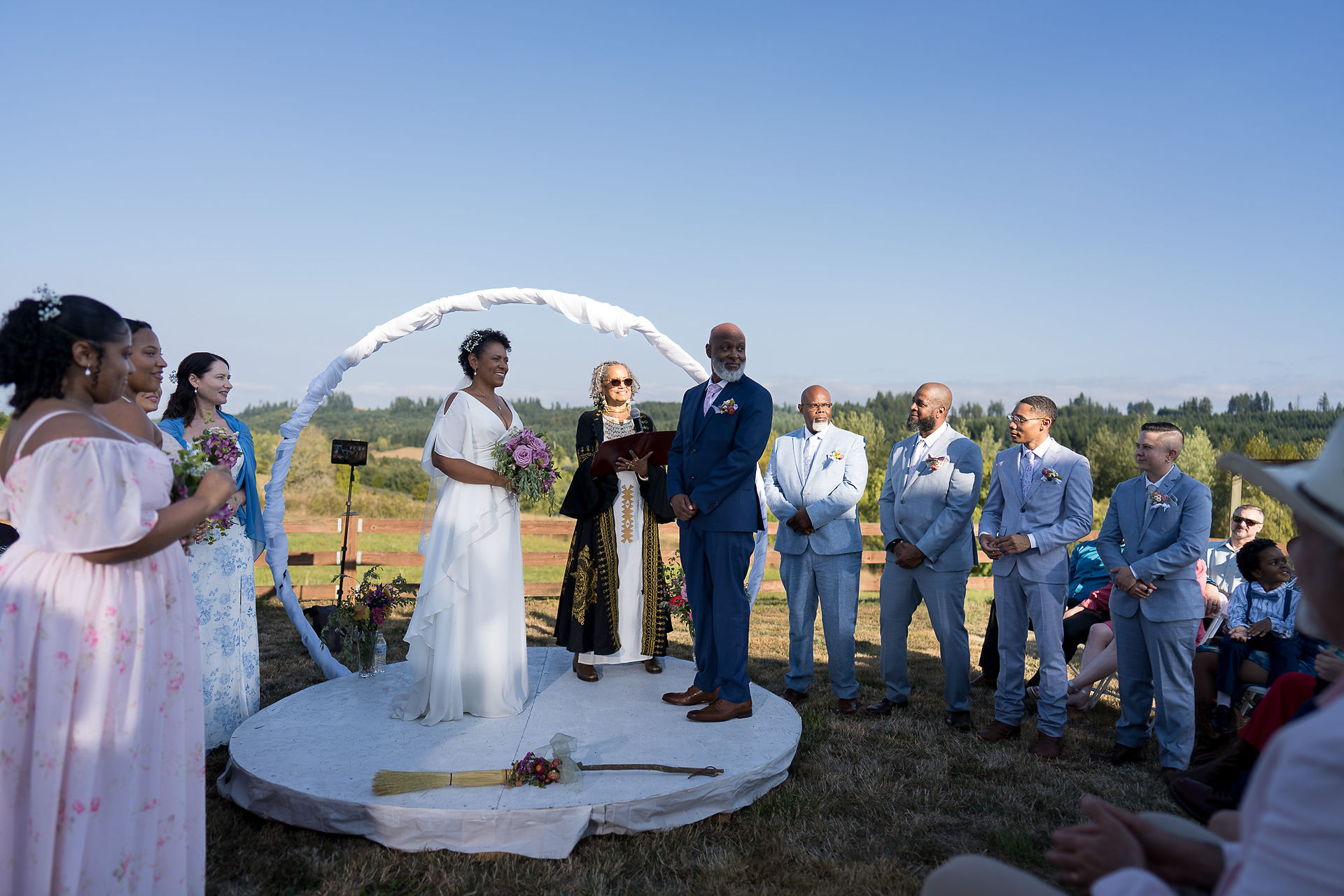 Bride and groom under arch at intimate farm wedding ceremony.
