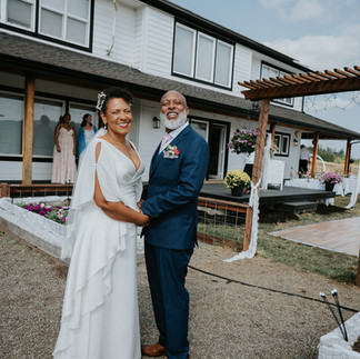 Joyful Black bride and groom hold hands at intimate farm wedding.