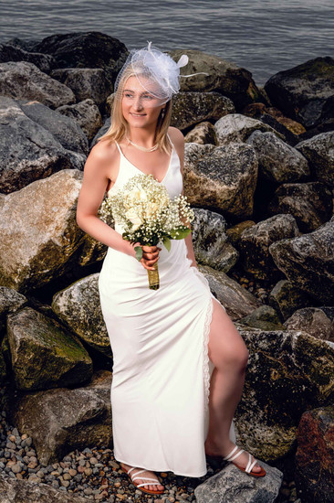 Bride in white dress holding bouquet near rocks