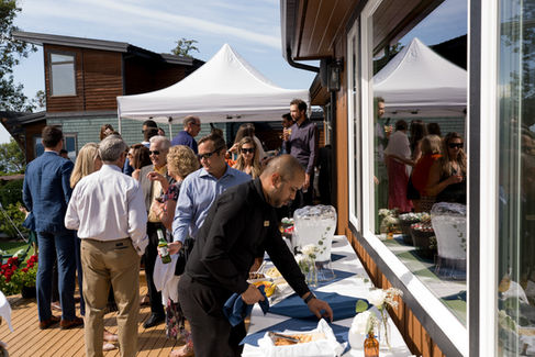 People gather for an outdoor wedding reception with white tents.