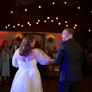 Bride and groom dancing at reception with string lights overhead.