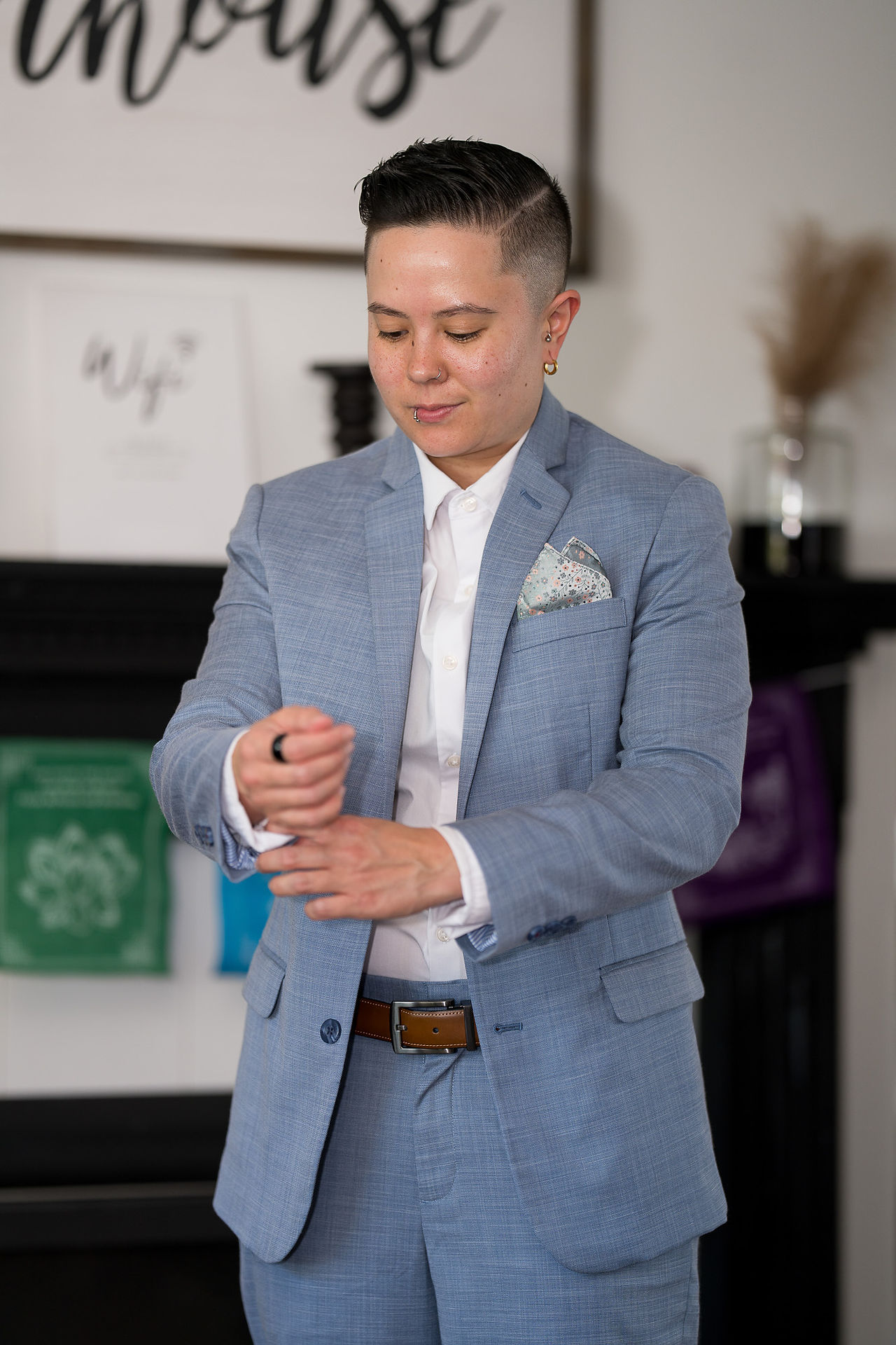 Stylish person in blue suit adjusts cuff, preparing for a wedding.