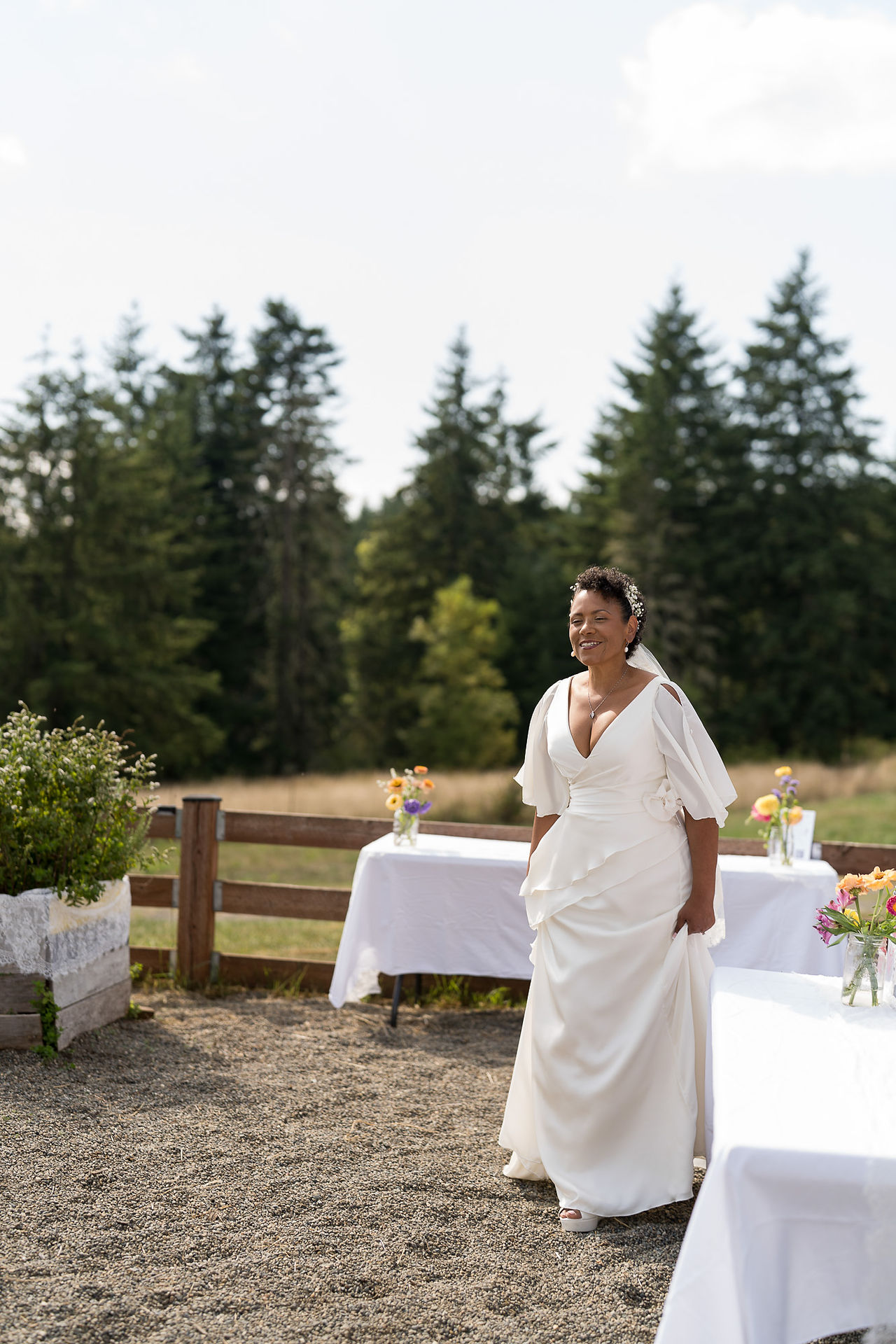 Smiling bride in white wedding dress at outdoor farm reception.