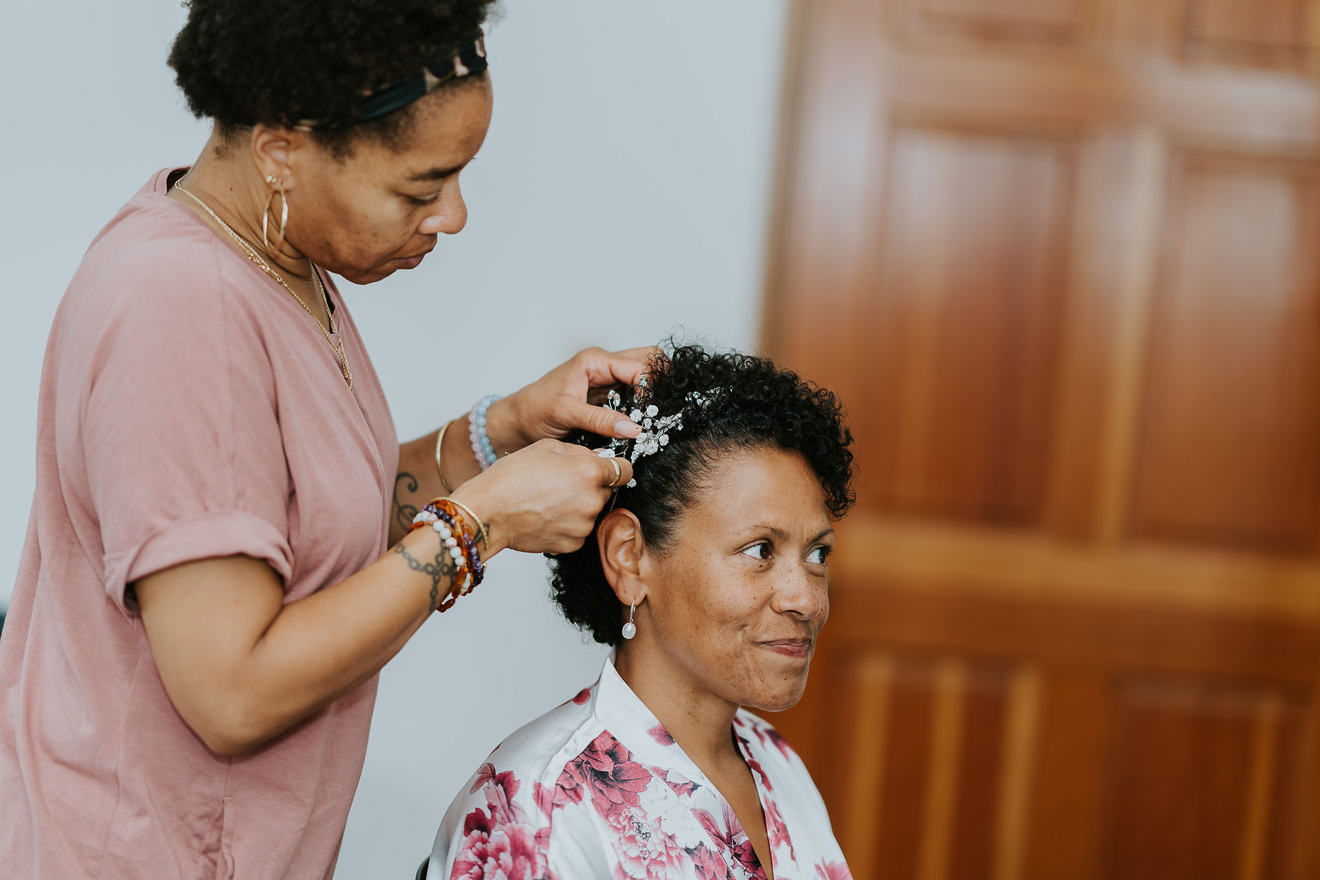 Hairstylist adding elegant hair accessory to woman's short curly hair.