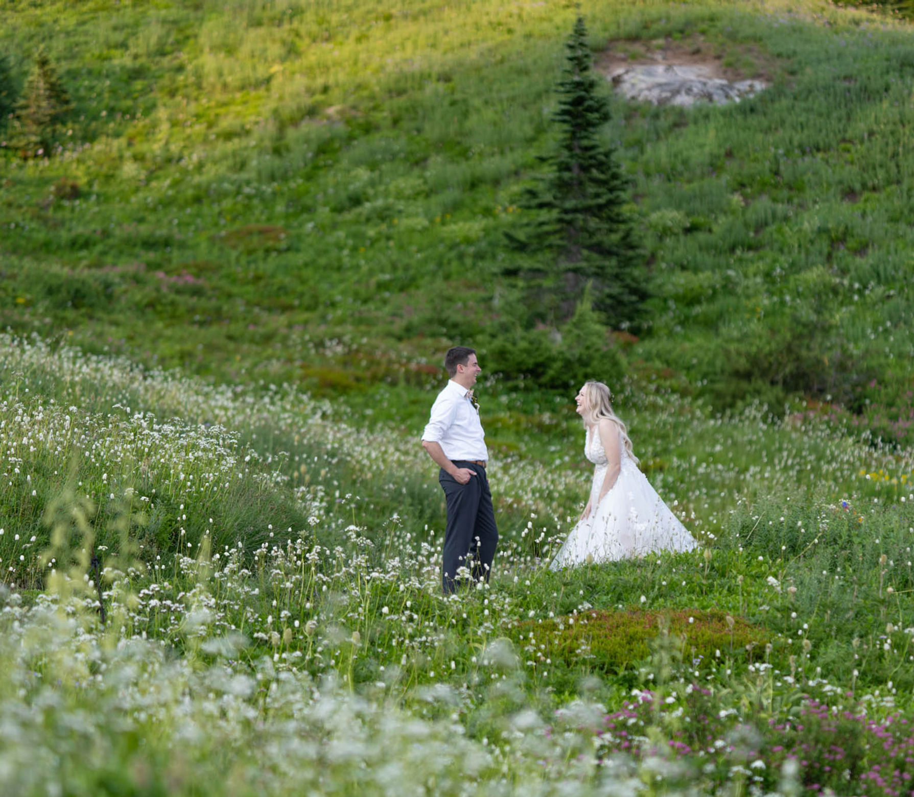 Bride and groom standing in a green alpine meadow during a Pacific Northwest adventure elopement