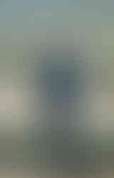 Happy older Black man in blue suit at an outdoor wedding.