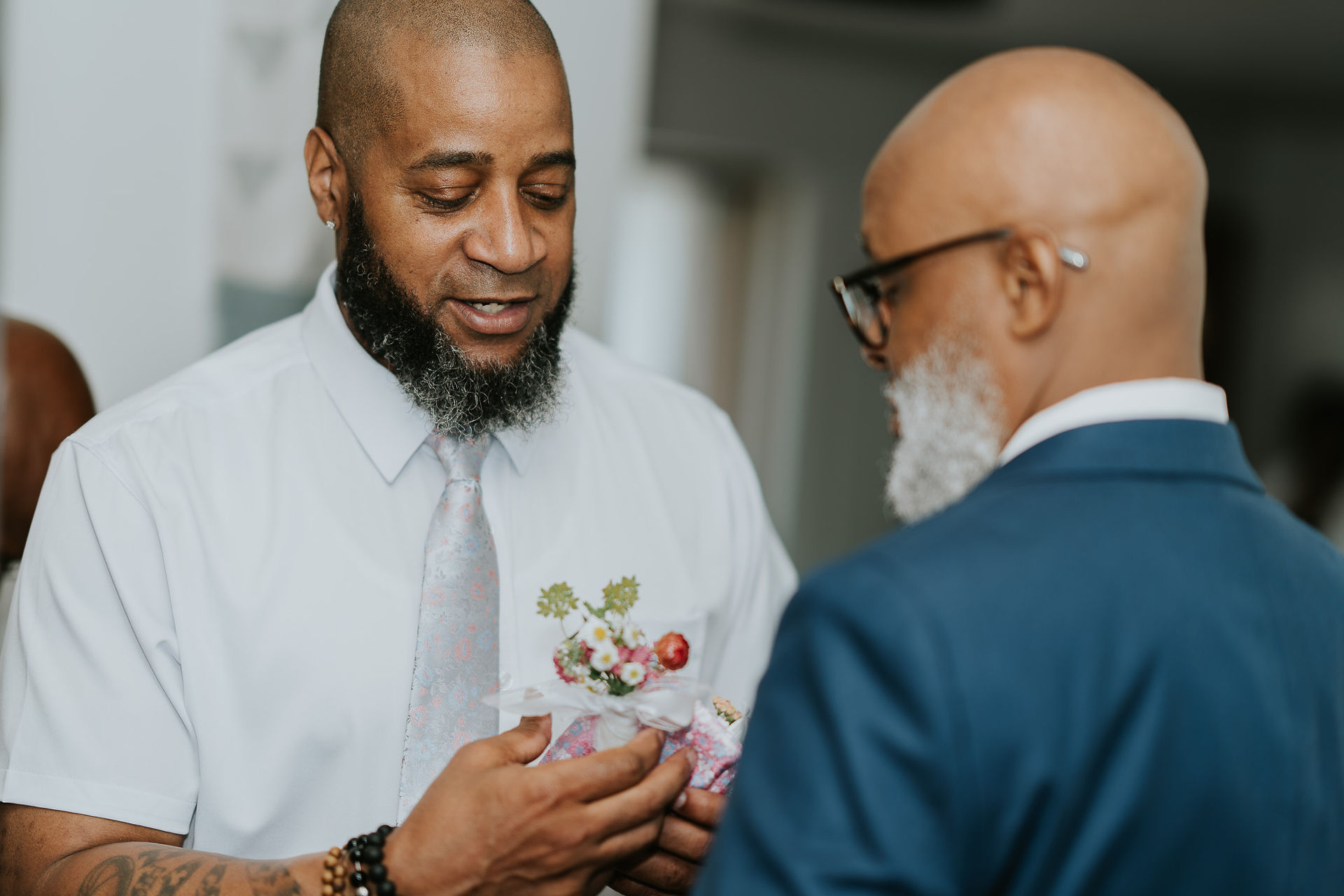 Groom in white shirt carefully holds floral boutonnière before wedding.