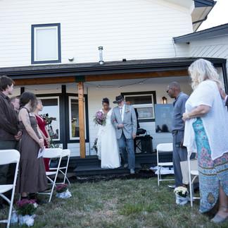 Bride walks with man down aisle during outdoor intimate wedding ceremony.