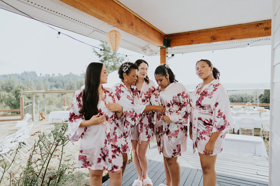 Five women in matching pink floral robes getting ready on porch.