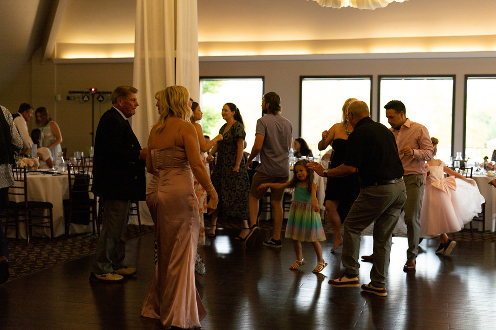 Guests dancing, including a young girl, at an indoor reception.