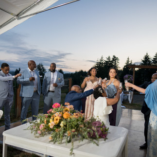Guests celebrate outdoors, raising drinks at a rustic evening wedding.