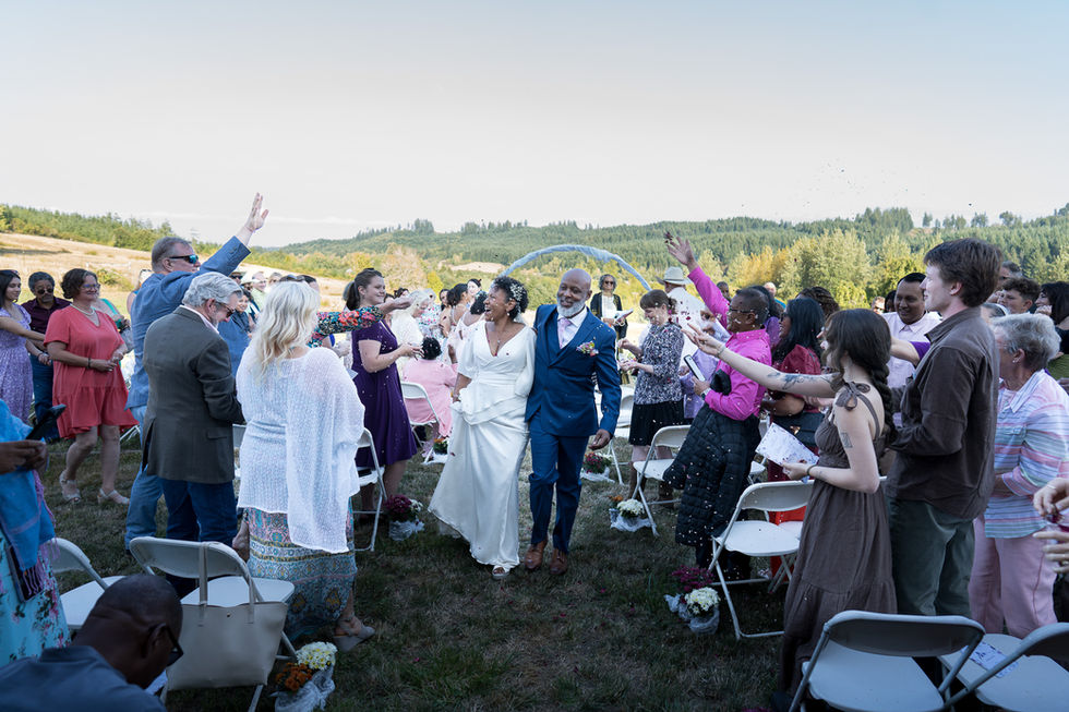 Newlywed couple walks through cheering guests at an intimate farm wedding.